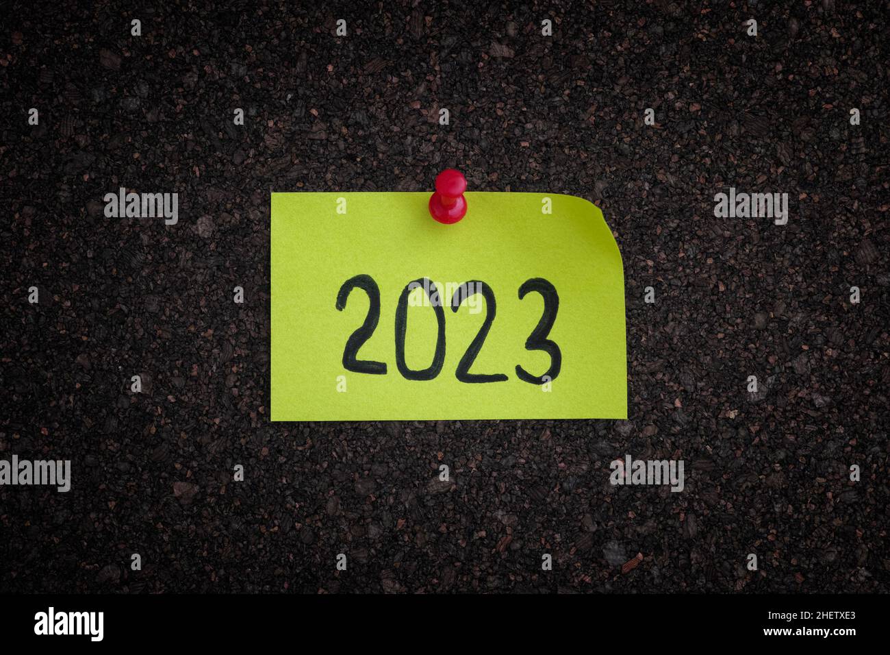 A sticky note with the year 2023 on it pinned to a cork board. Close up. Stock Photo