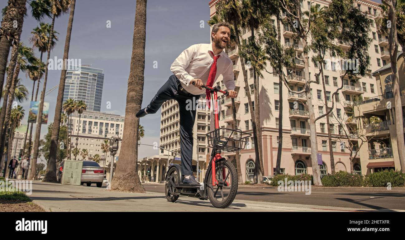 Happy employer in formalwear have fun riding escooter on sidewalk, recreation Stock Photo