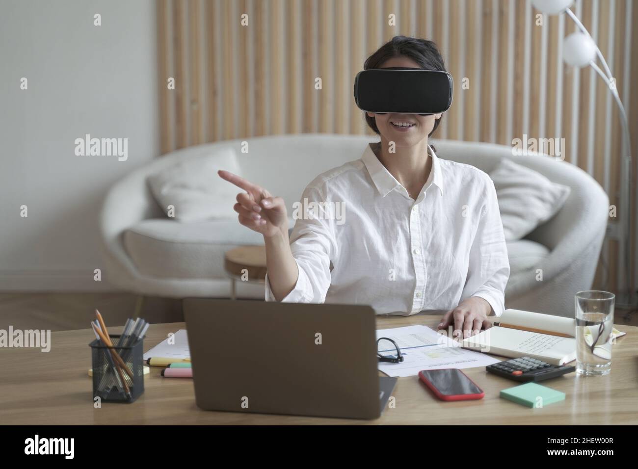 Female office worker in vr headset or virtual reality goggles touching objects in cyberspace Stock Photo
