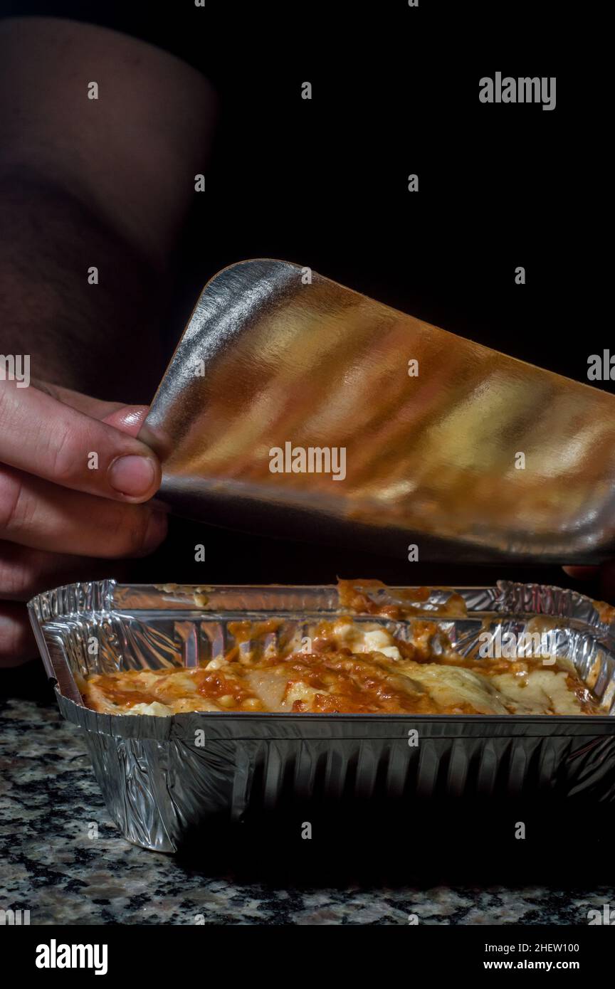 https://c8.alamy.com/comp/2HEW100/lasagna-in-an-aluminum-pan-spatula-taking-a-piece-of-the-pan-selective-focus-2HEW100.jpg