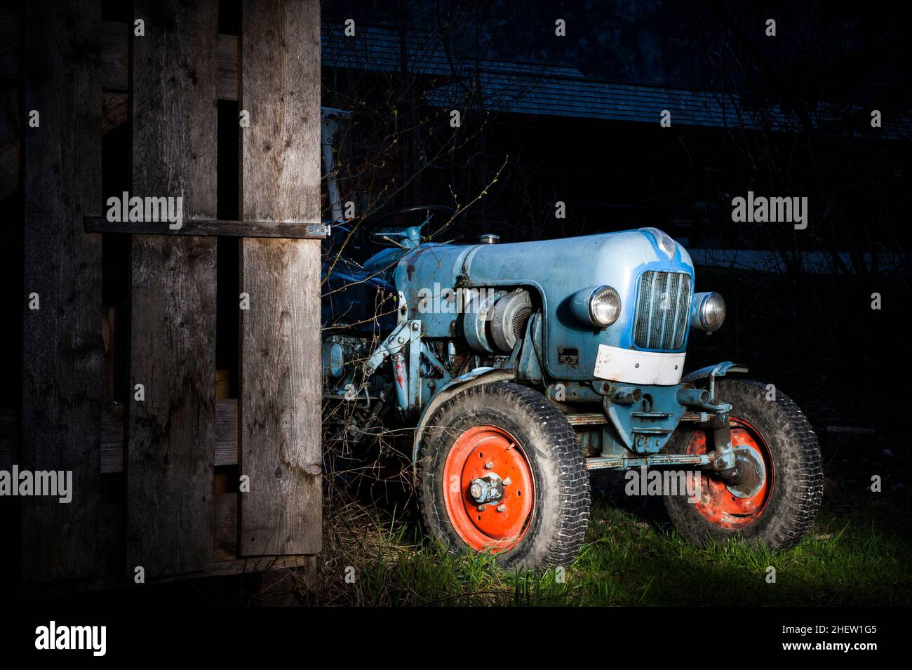 blue oldtimer farming tractor standing next to a wooden hut at night