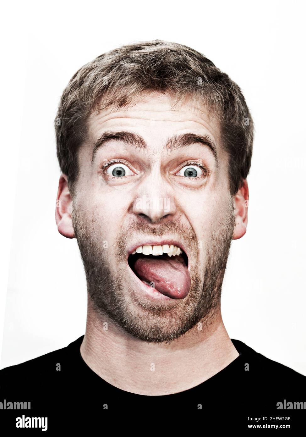 young blonde man makes grimace with mouth wide open and tongue outside Stock Photo