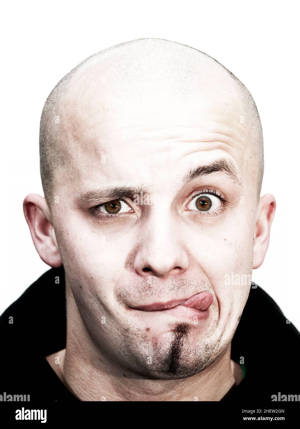 young bald head teenager makes grimace with tongue outside and beard at his chin on white background Stock Photo