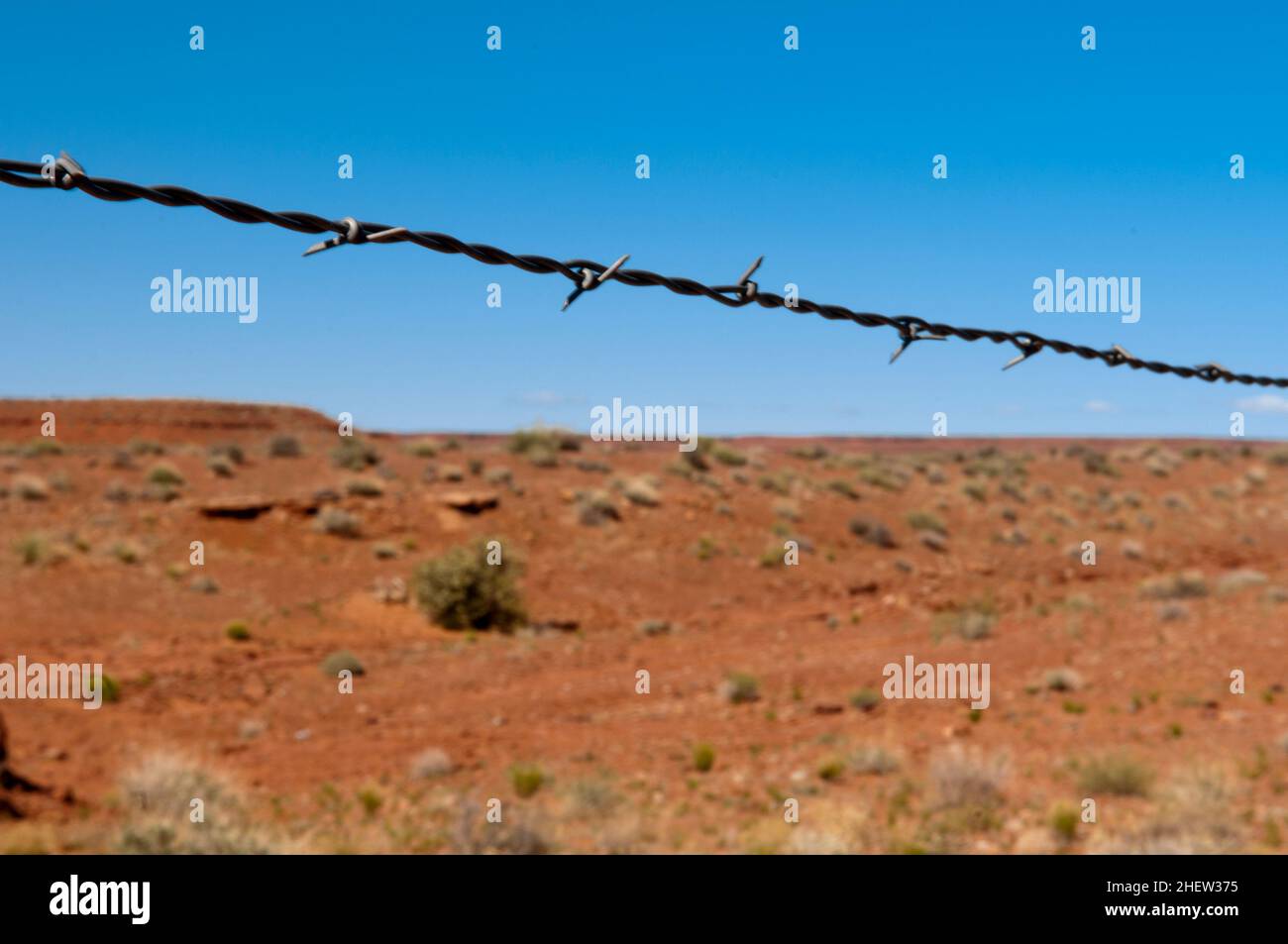 barbed wire as divider to the hot red desert with blue sky Stock Photo
