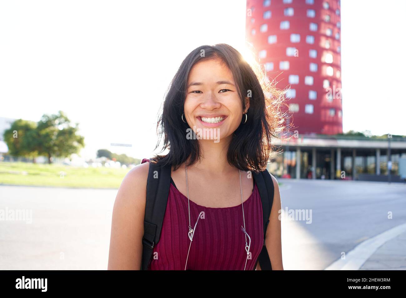 Portrait of a beautiful young woman in Barcelona. She is Asian, on her early twenties, brunette with long hair. Looking at camera and smiling. Smart Stock Photo