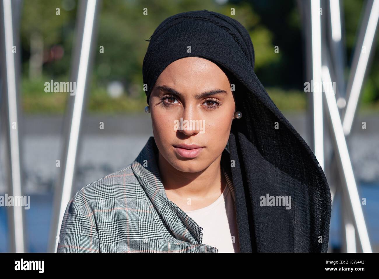 Portrait of a muslim adult woman wearing a black headscarf looking at camera in the park Stock Photo