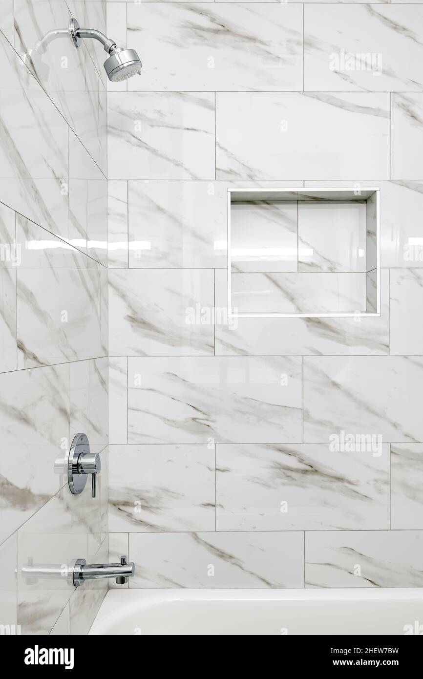 Modern White and Gray Large Marble Tile in BathTub with Toiletry Recess in Wall and Stainless Steel Fixtures Stock Photo