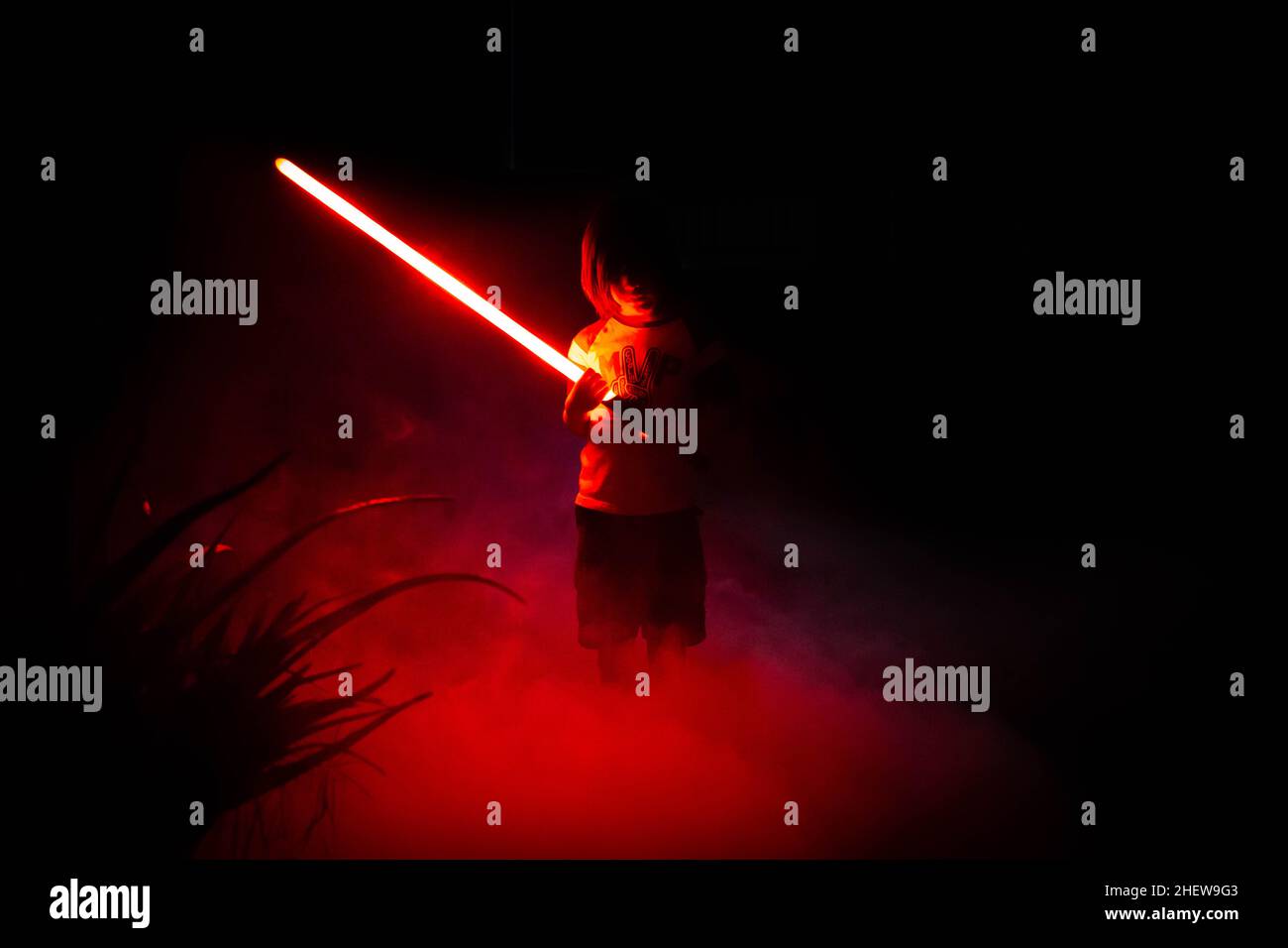 5 year old boy playing outside with lightsabers Stock Photo Alamy