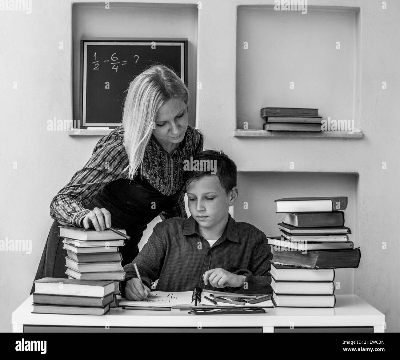 A junior high school student studying at home with a tutor. Black and white photo. Stock Photo