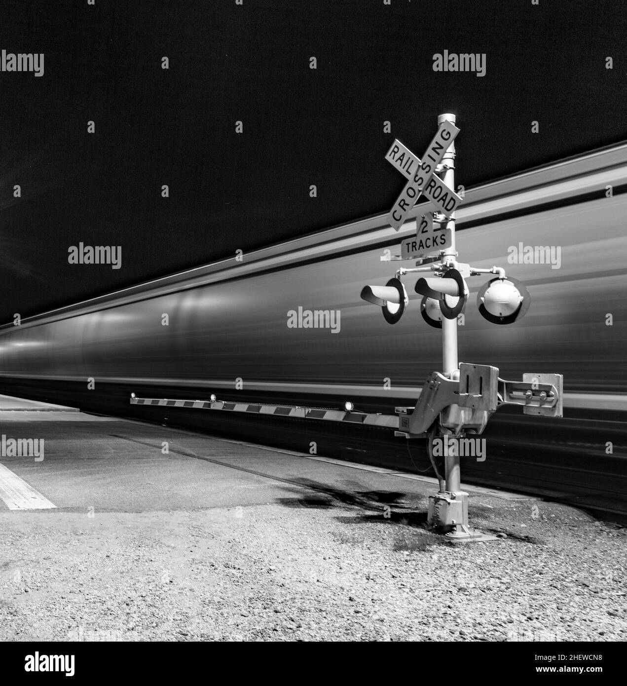 Railroad crossing with passing train by night Stock Photo Alamy