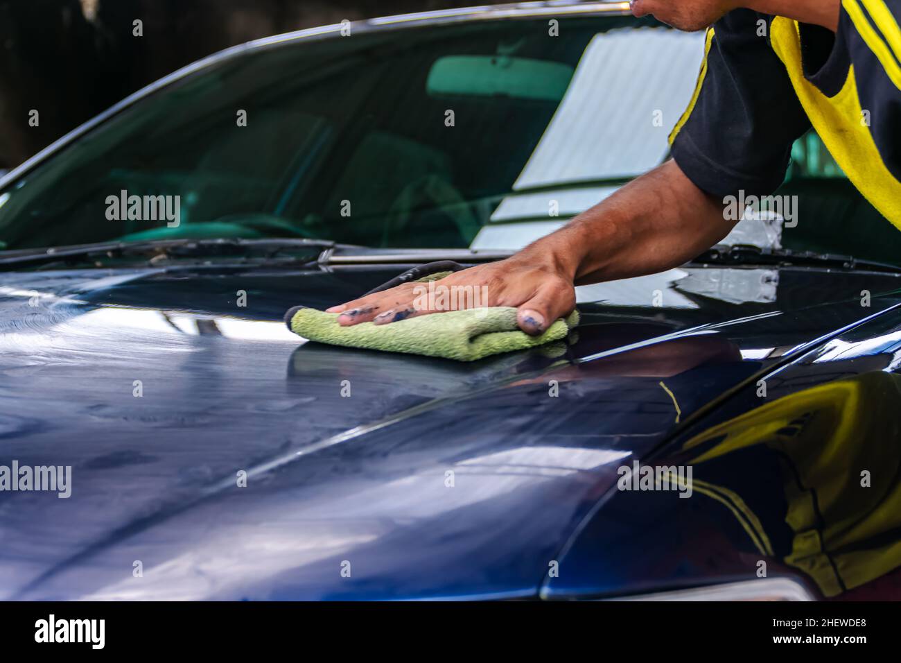 Man working on the auto garage. Rub and polish blue car or