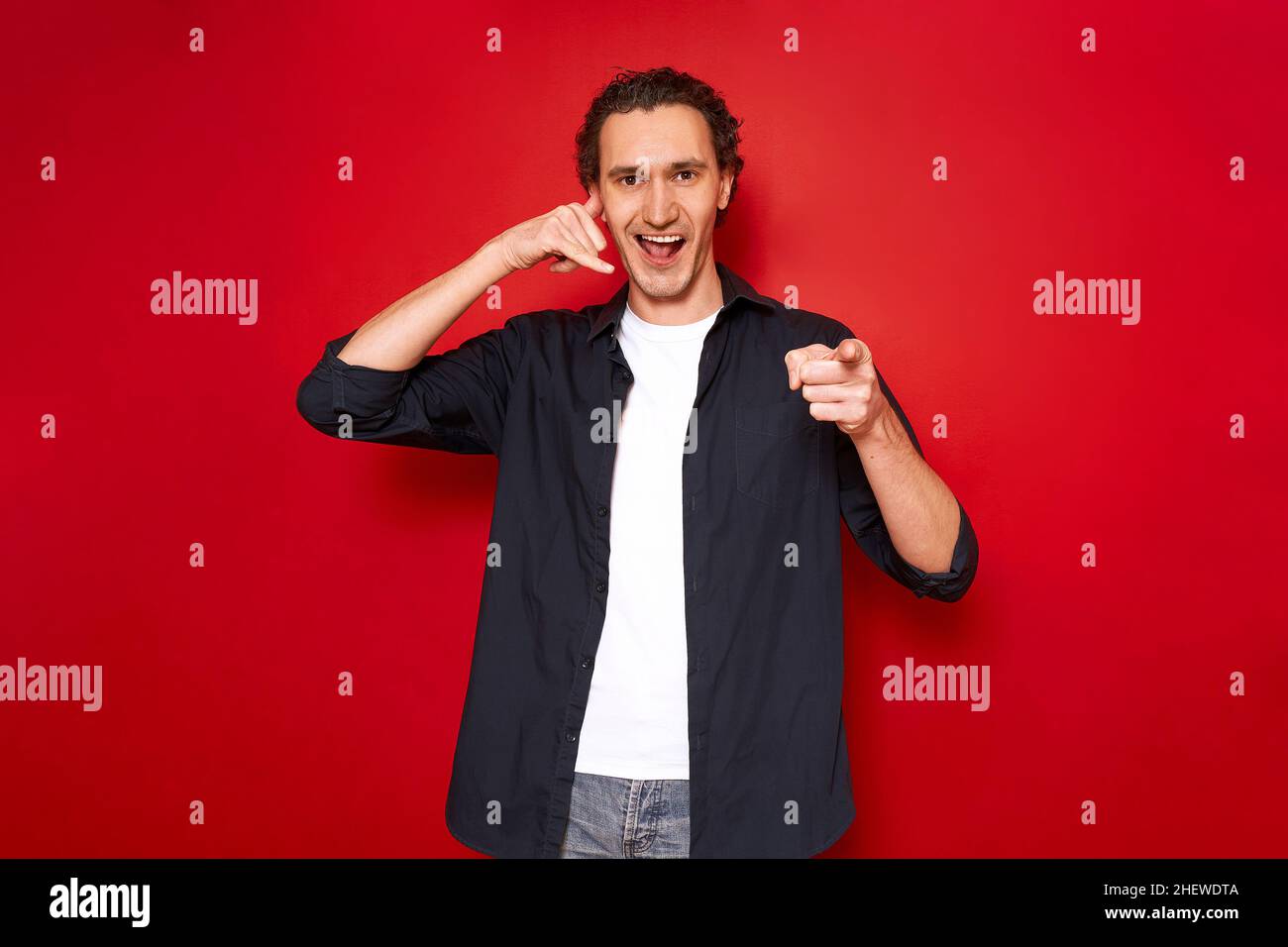 call me hand sign. portrait of young smiling man pointing index finger ...