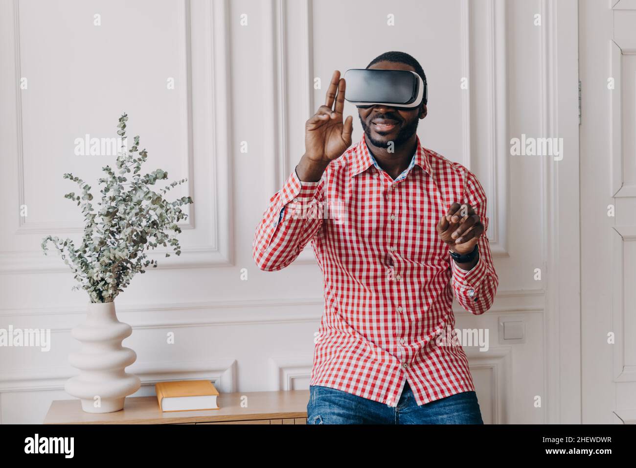 Excited cheerful african man wearing VR glasses totaly immersed in augmented reality of 3d games Stock Photo
