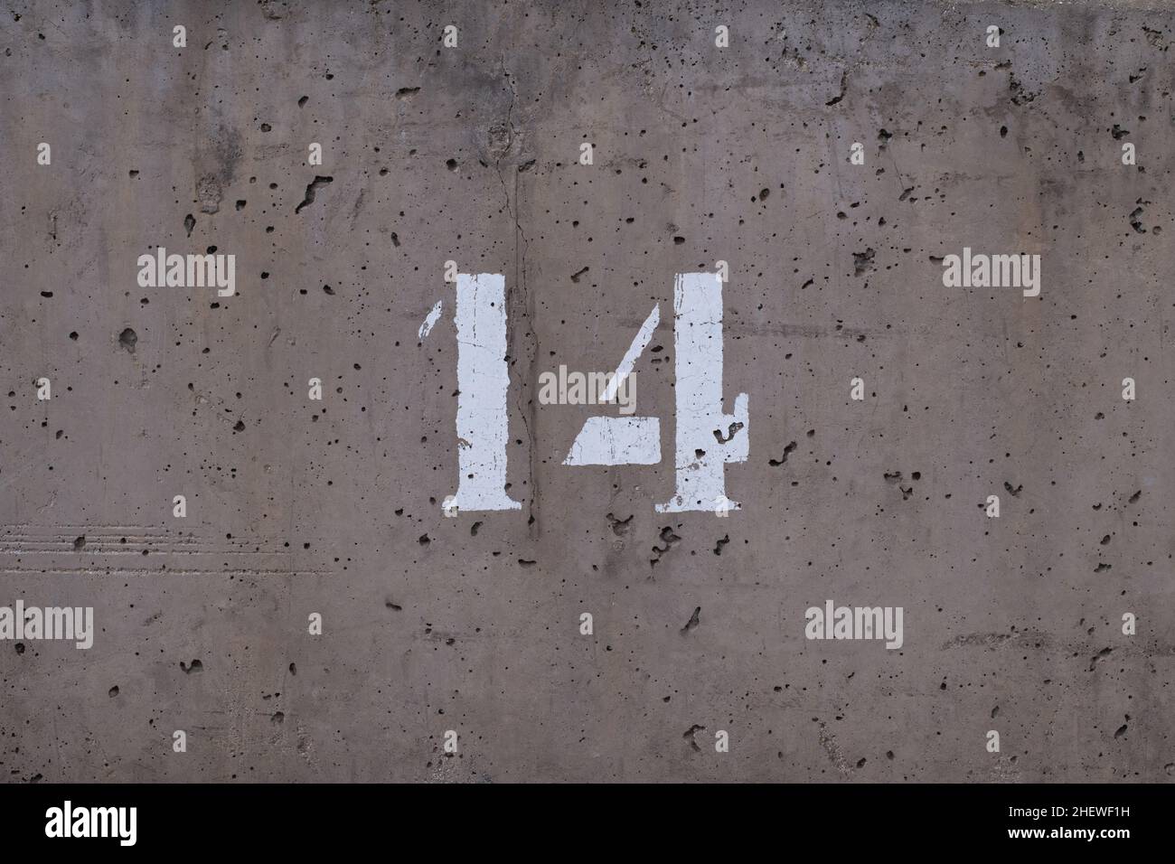 polished, stippled and weathered concrete wall with the number 14 Stock Photo