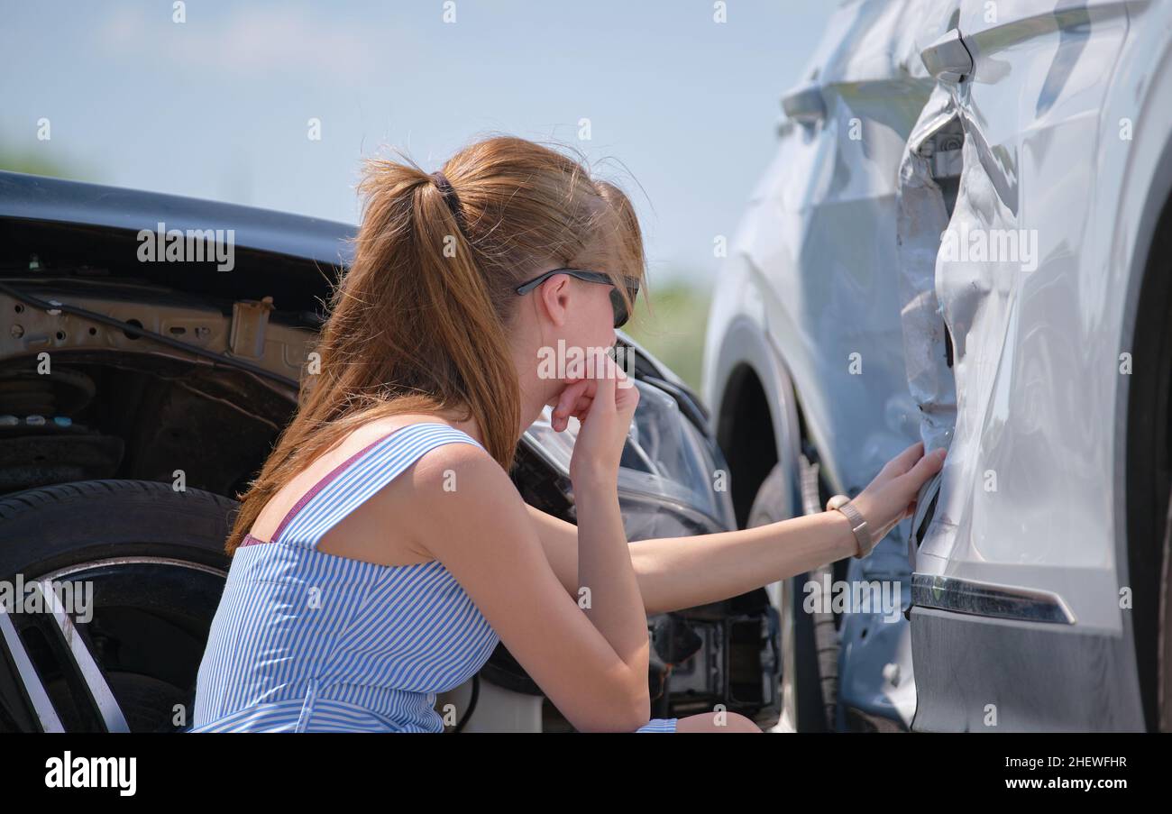 Sad female driver sitting on street side shocked after car accident ...