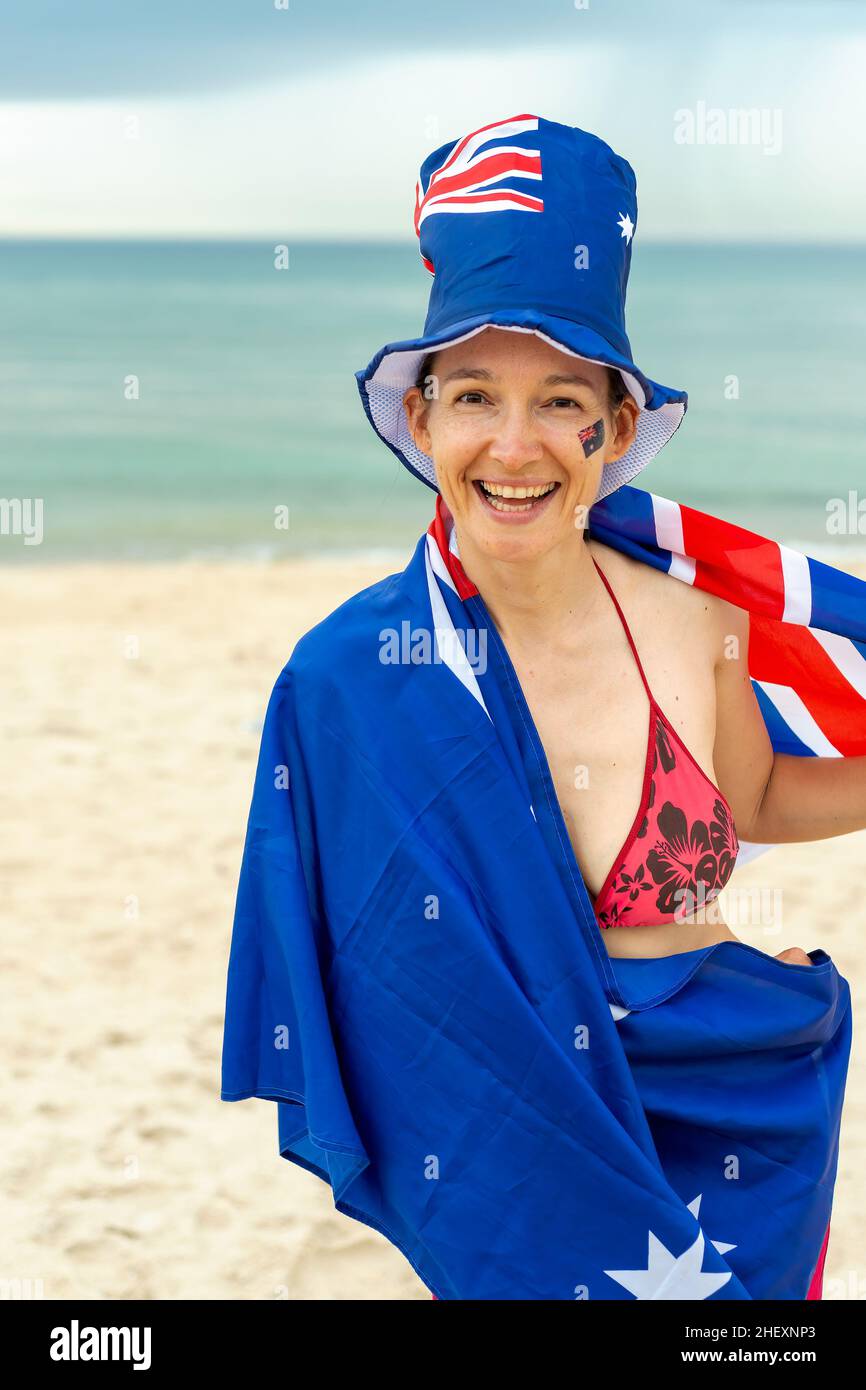 Happy woman in Australia hat waving Australian flag at beach. Concept