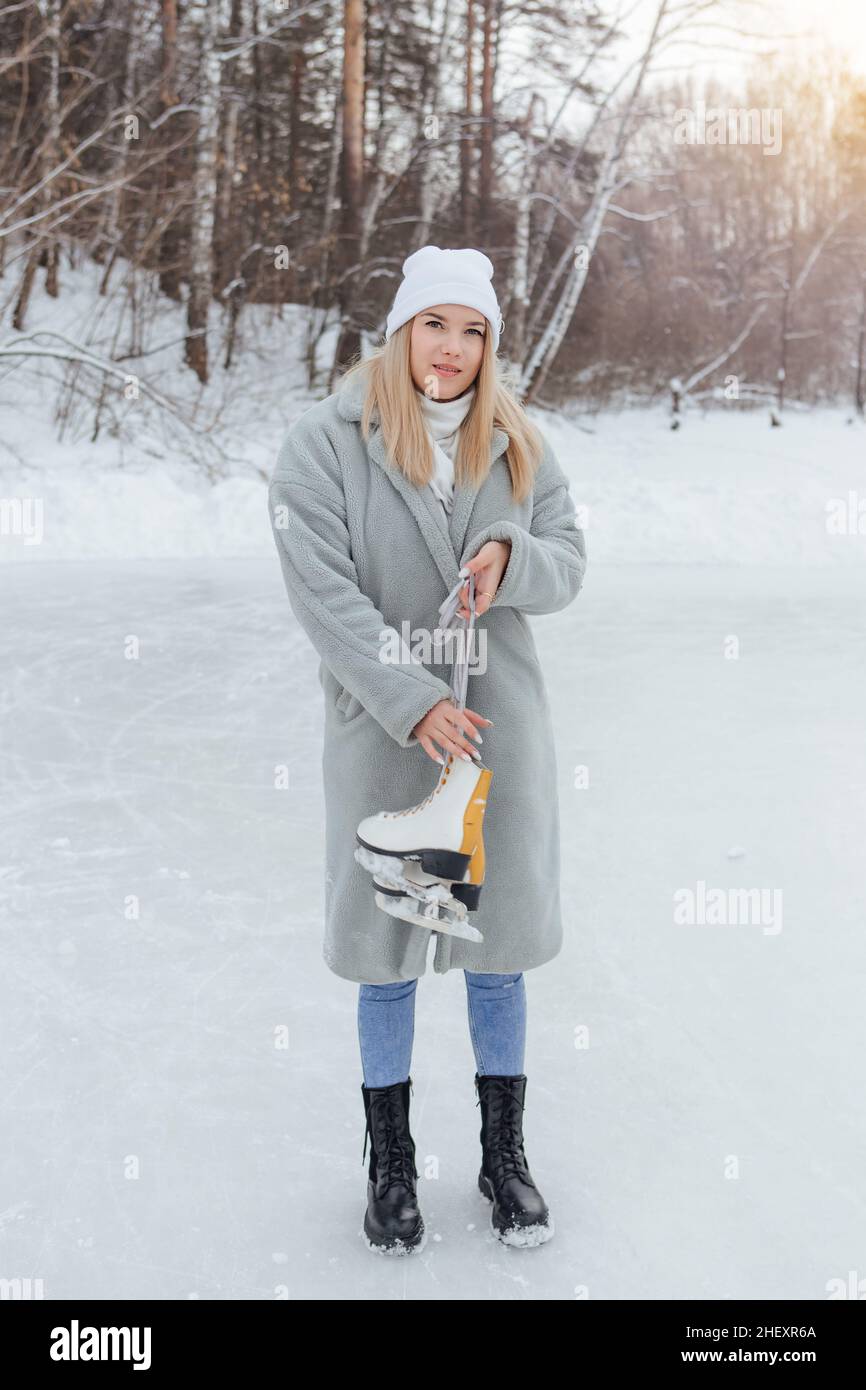 Lovely young woman with ice skates on the ice rink. Girl is going to skating on ice in a winter frosty day Stock Photo