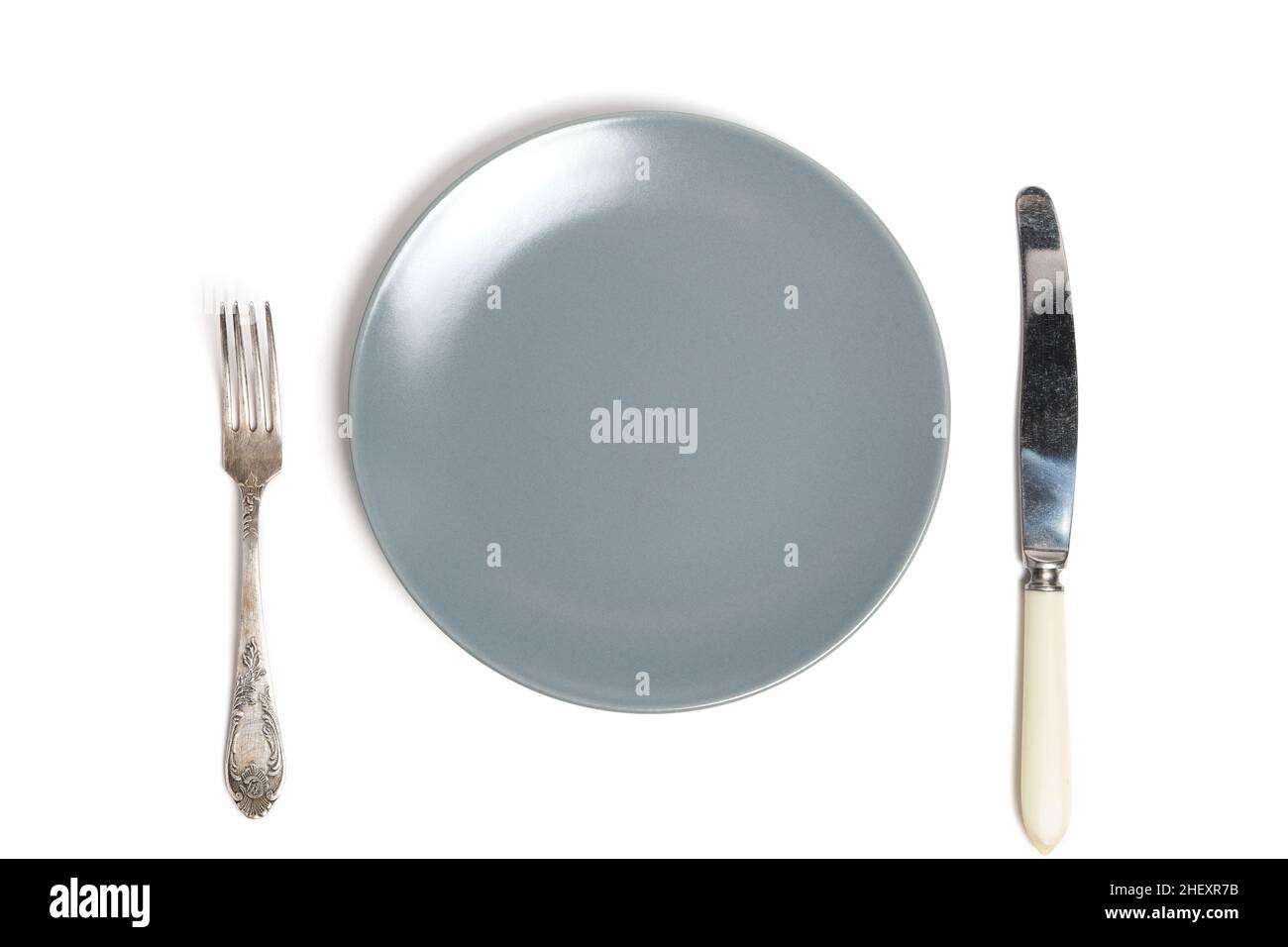 Empty grey plate and cutlery fork and knife white background Stock Photo