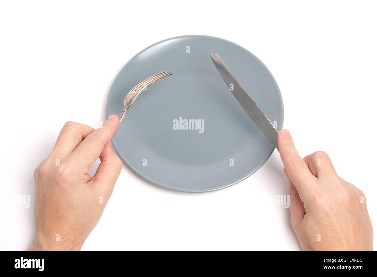 Empty plate and hands with cutlery spoon and fork white background Stock Photo