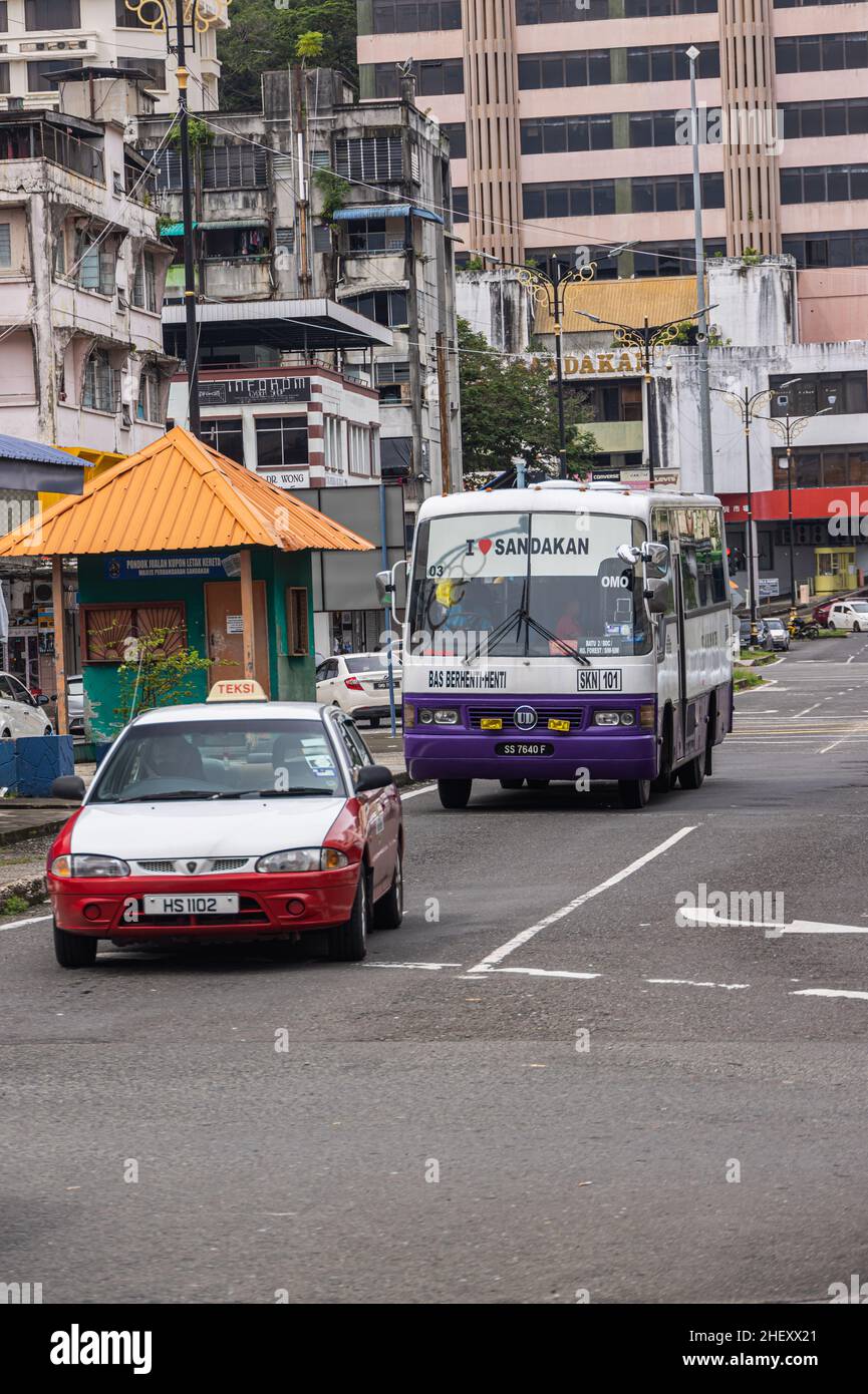 Sandakan, Malaysia - January 05, 2022: Old taxi and an old Bus in the town of Sandakan. Driving bus in city traffic. Public transport at Sabah, Borneo Stock Photo