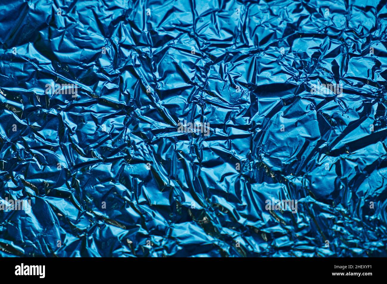 Close-up of crumpled silver aluminum foil texture in blue tone. Abstract background for design. Stock Photo
