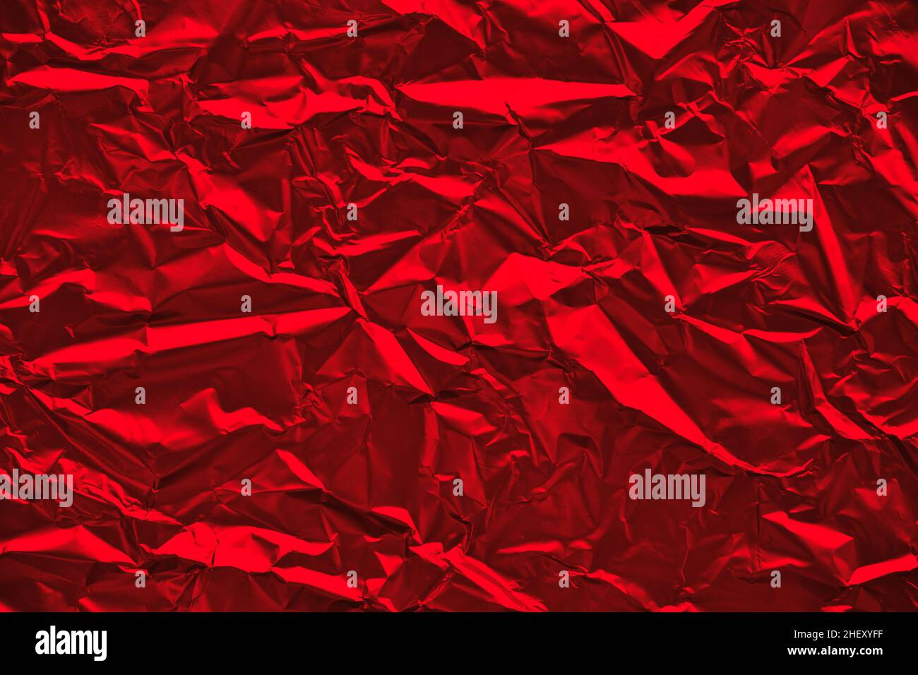 Close-up of crumpled silver aluminum foil texture in red tone. Abstract background for design. Stock Photo