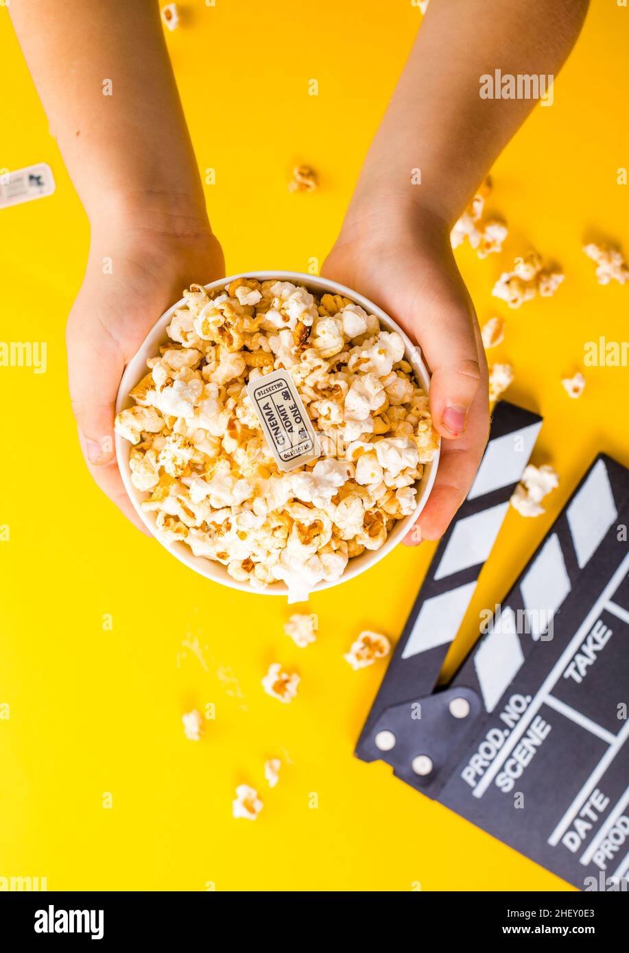 Popcorn viewed from above on yellow background. Child eating popcorns