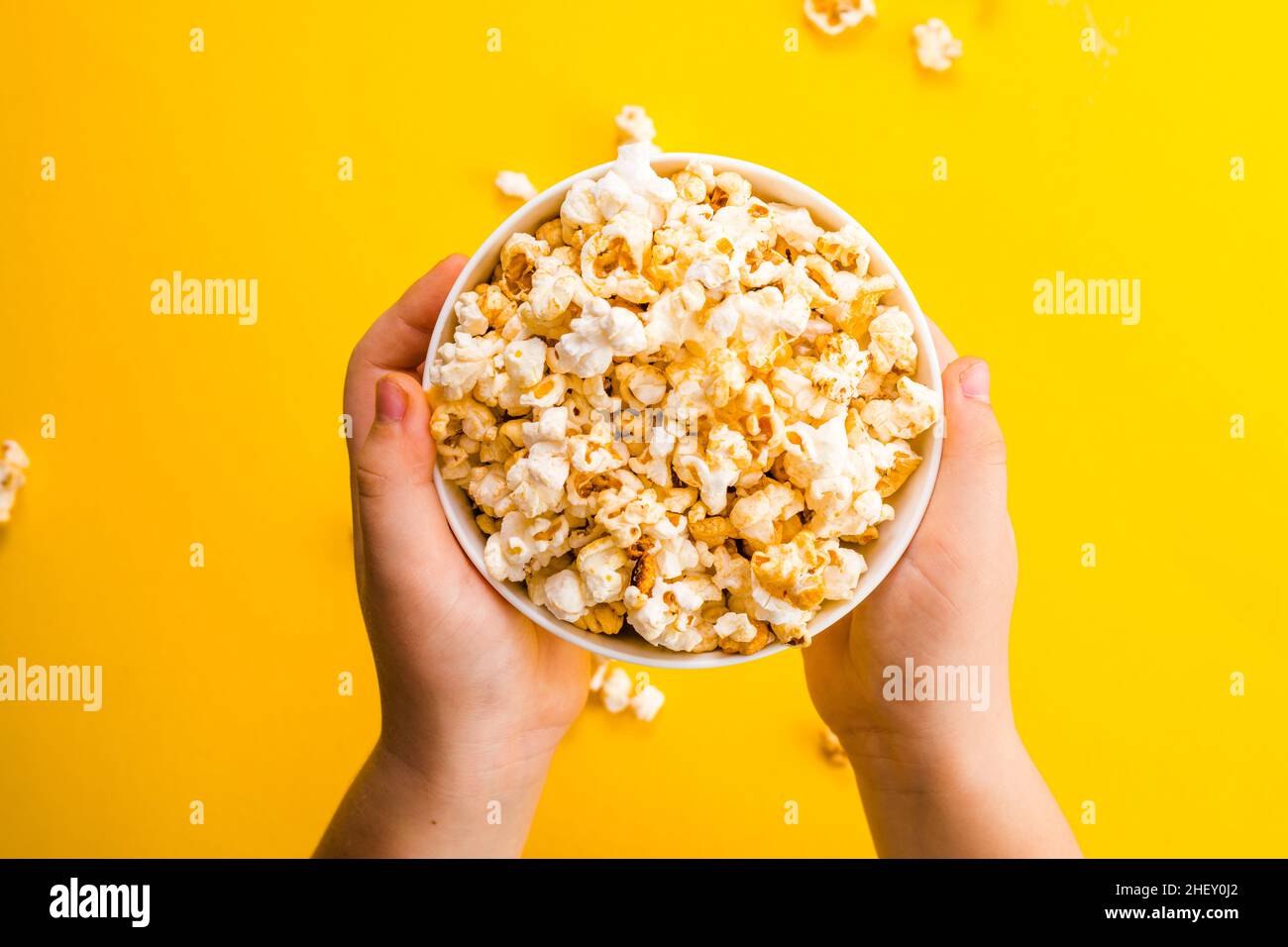 Popcorn viewed from above on yellow background. Child eating popcorns