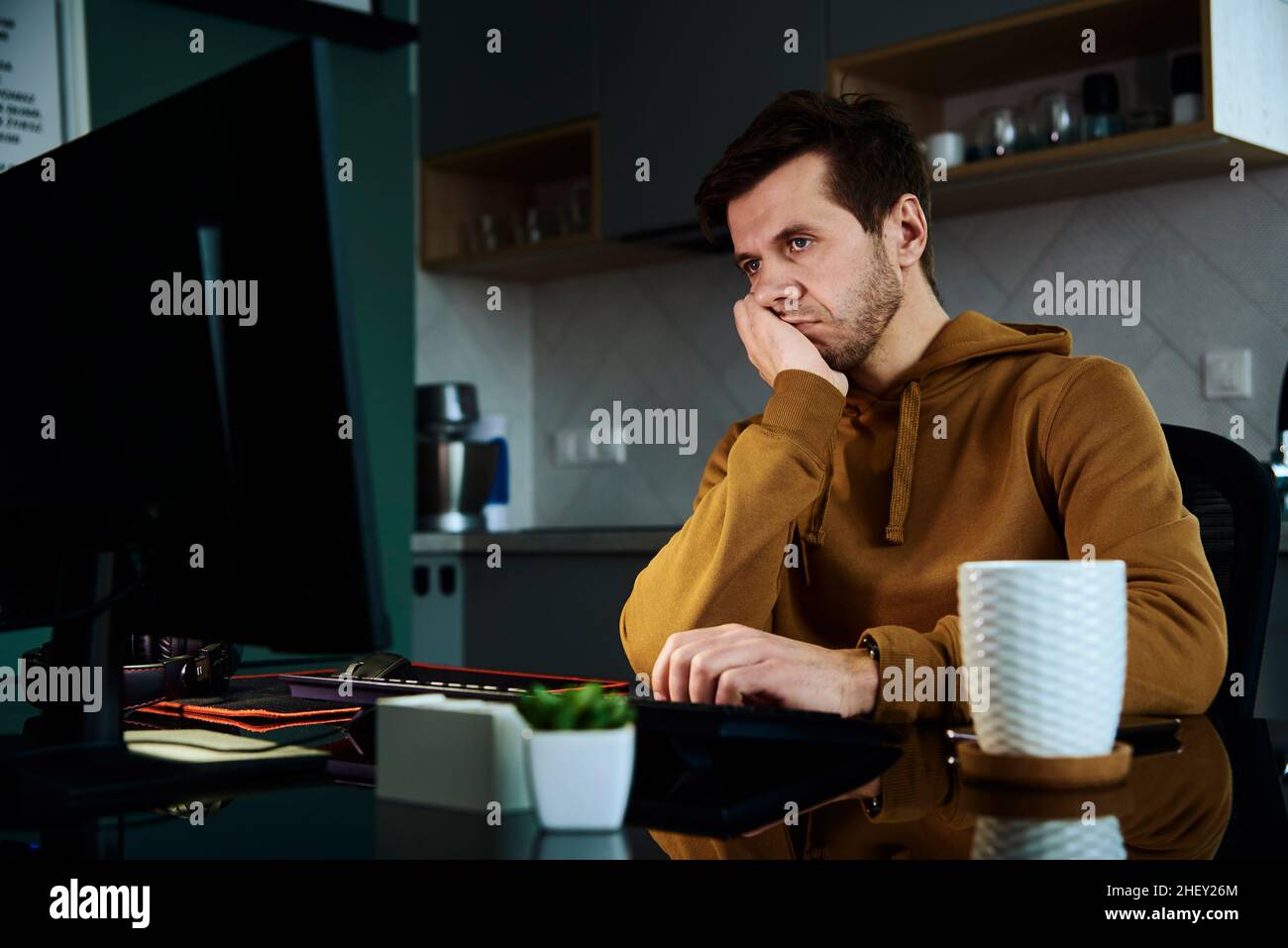 Man works late at home workplace, remote work concept. Burnout and emotional stress due to overworking Stock Photo