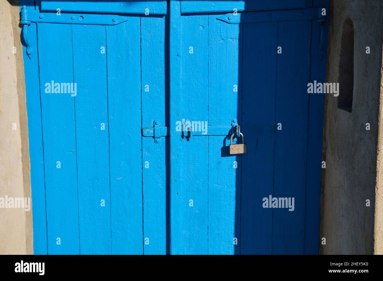 ancient blue painted wooden gate with a lock on the right side Stock Photo