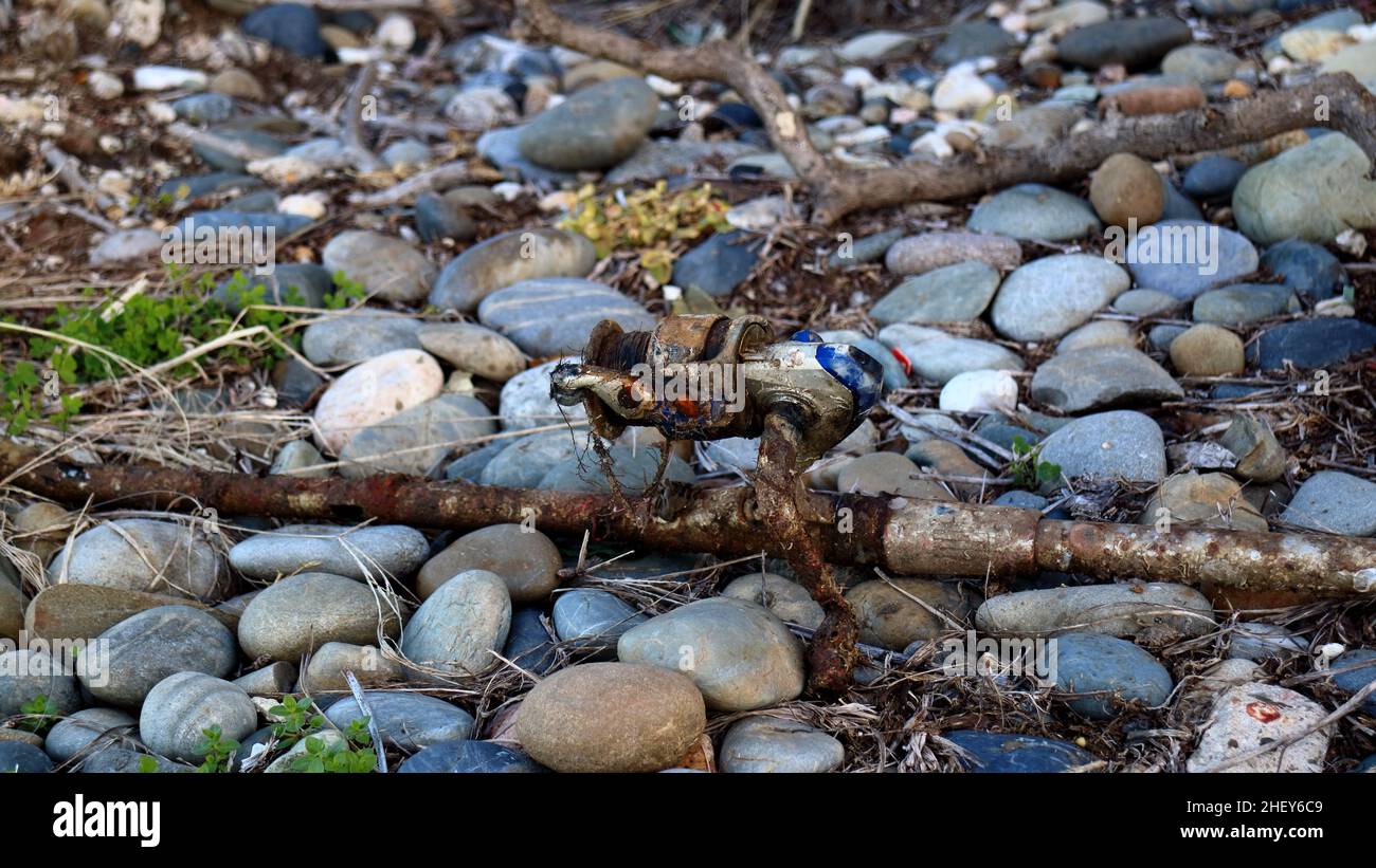 old and rusty fishing rod on river pebbles. Shot on the