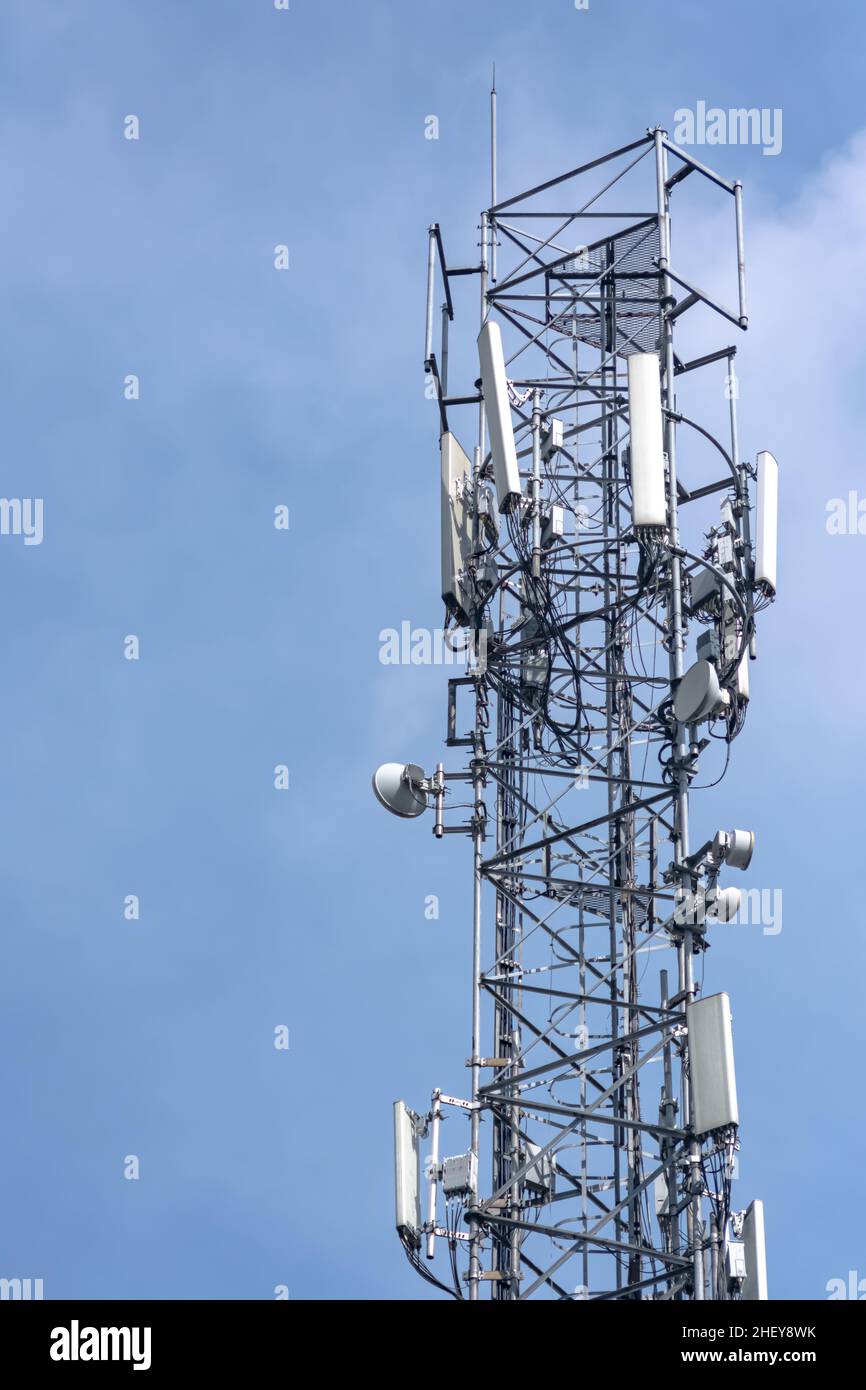 tall telecommunication tower or transmitter broadcasting the internet network and mobile data at the cloudy sky background Stock Photo