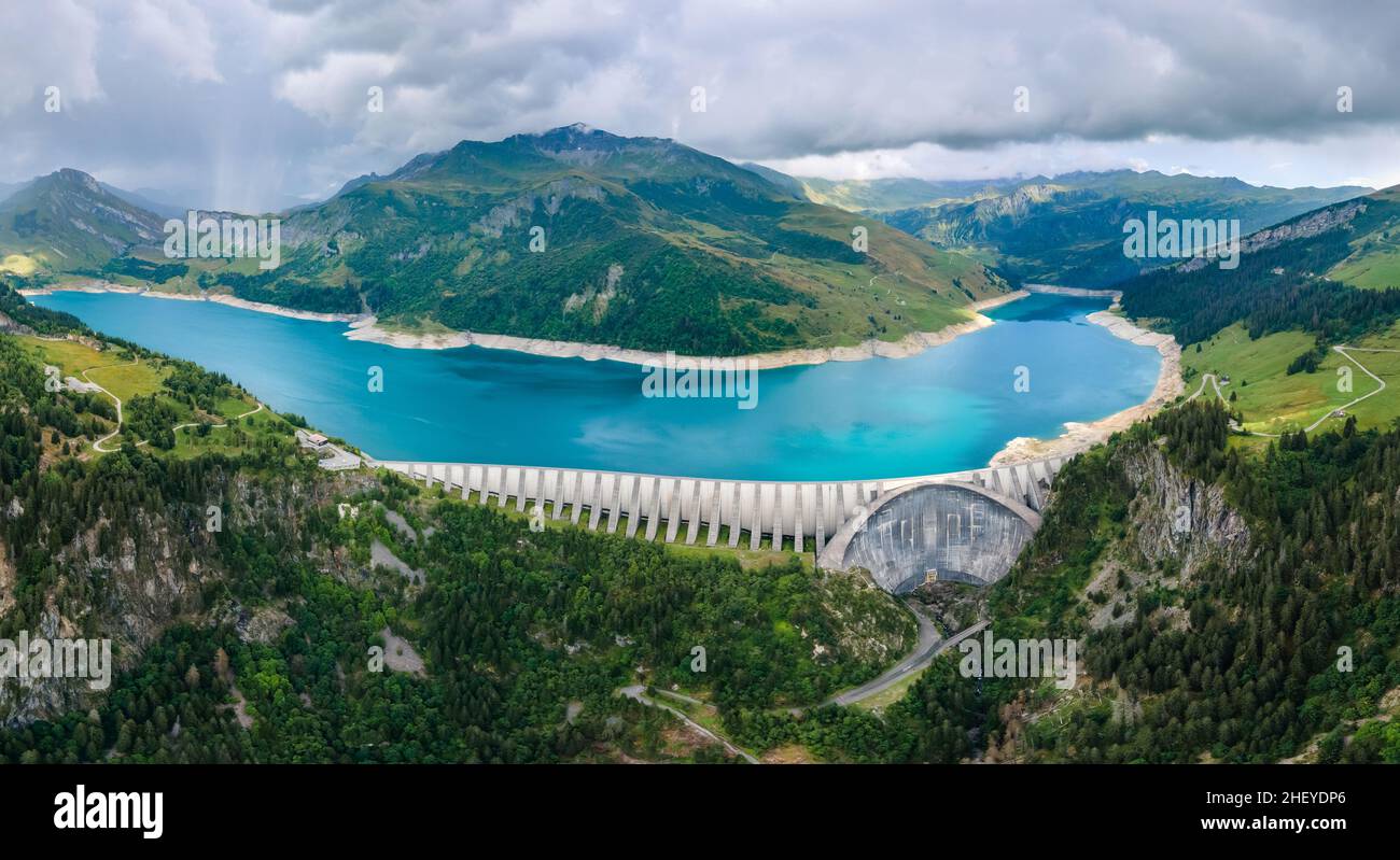 Hydroelectric dam and reservoir lake in French Alps mountains. Renewable energy and sustainable development with hydropower generation. Aerial view. Stock Photo