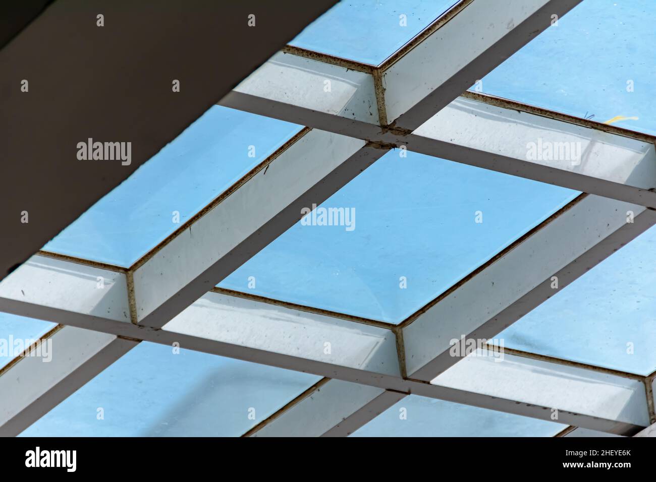 metal structure of white canopy with tempered glass covering upside under the clear and bright blue sky Stock Photo