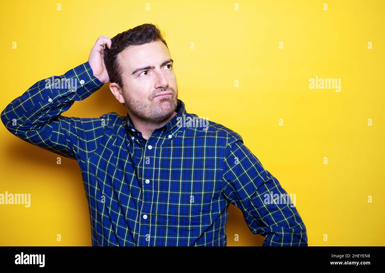 One man isolated on yellow background feeling puzzled and doubtful Stock Photo