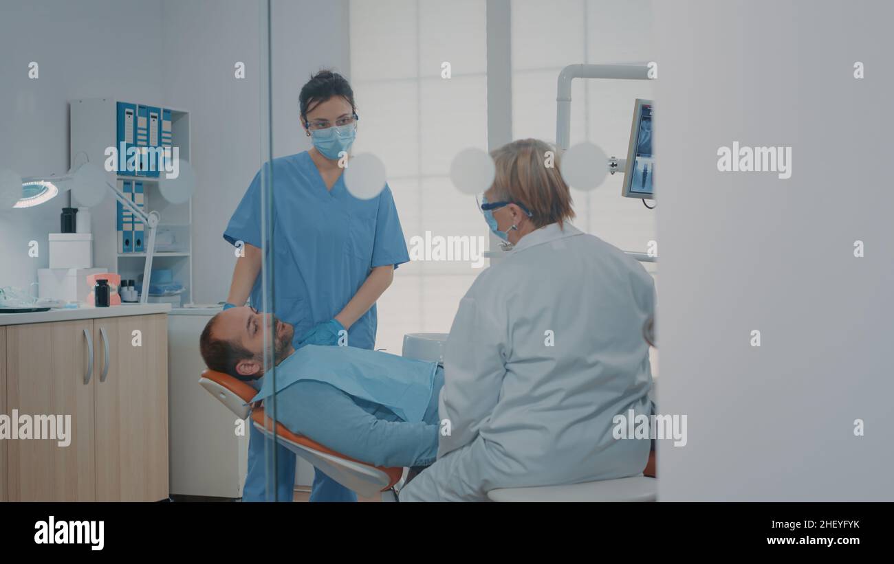 Orthodontist using dental tools to do teeth examination on patient with