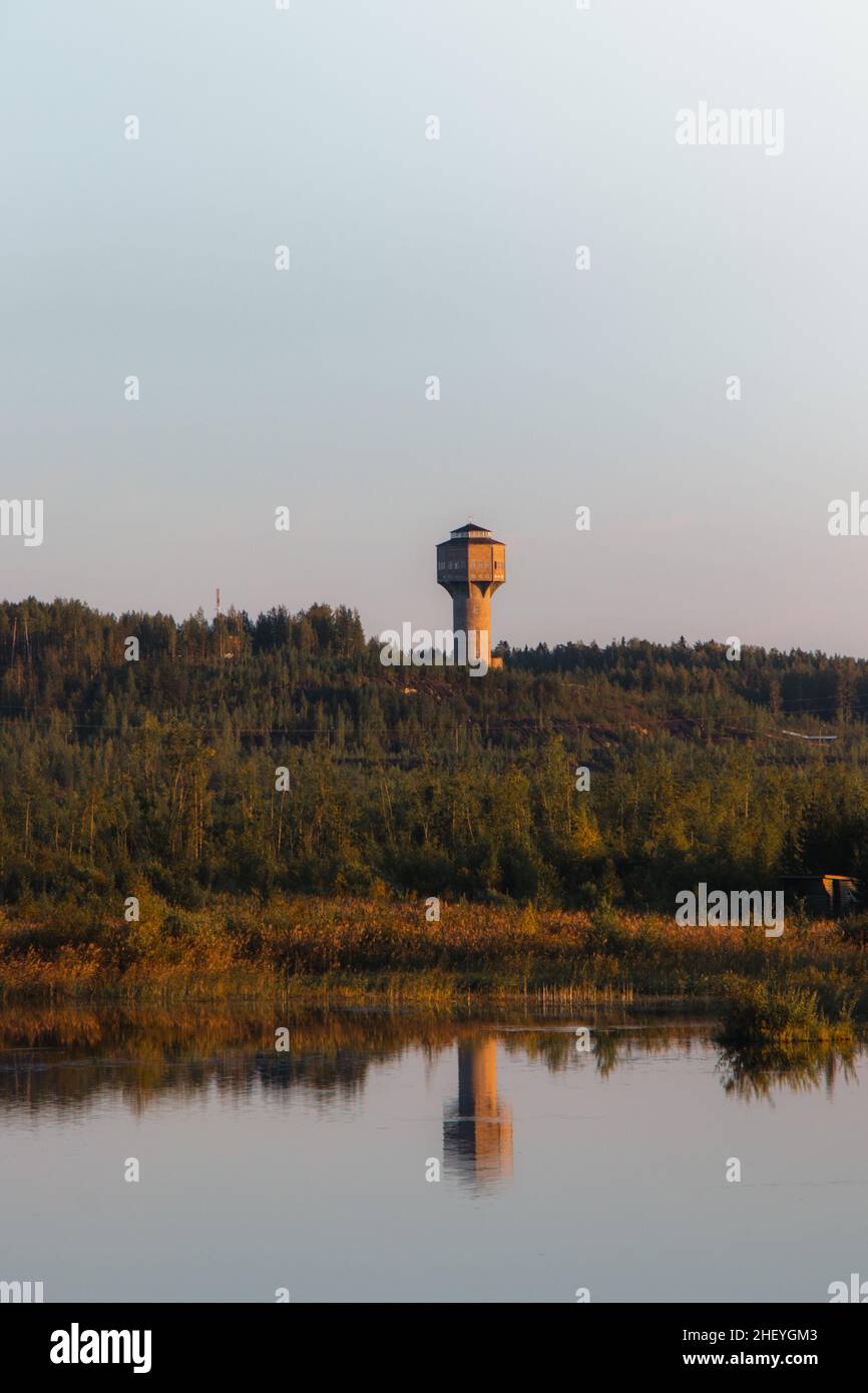 view of an abandoned mining tower by the infernal golden light near Kajaani, in the Kainuu region of central Finland. The tower is reflected on the la Stock Photo