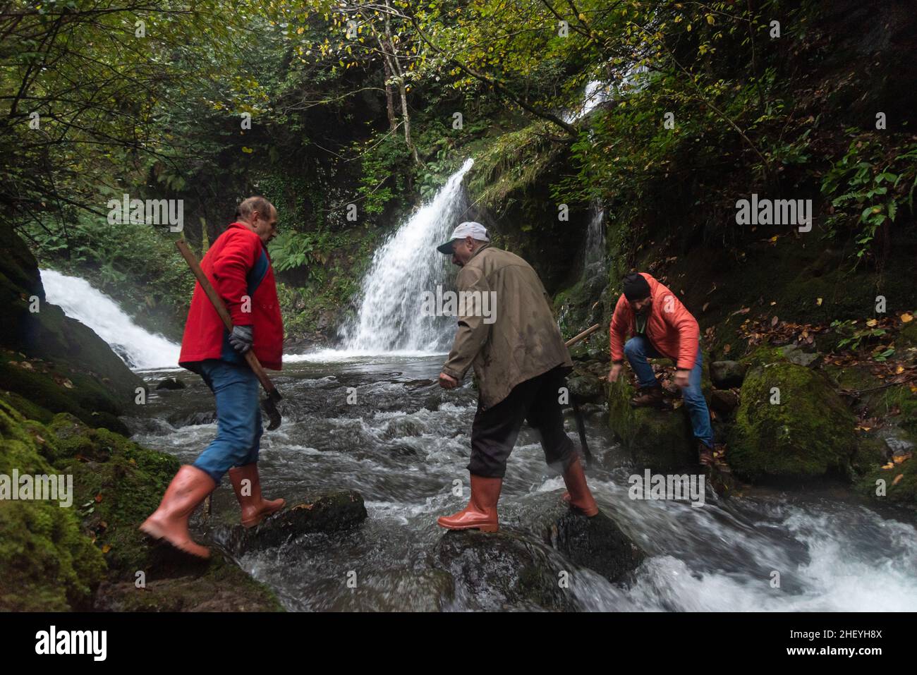 The men help each other as they pass over the waterfall. Ordu, Turkey. Stock Photo