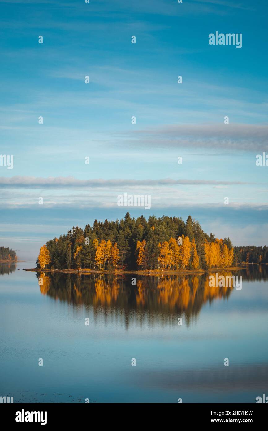 Autumn forest on a small island coloured in autumn colours. Reflection ...