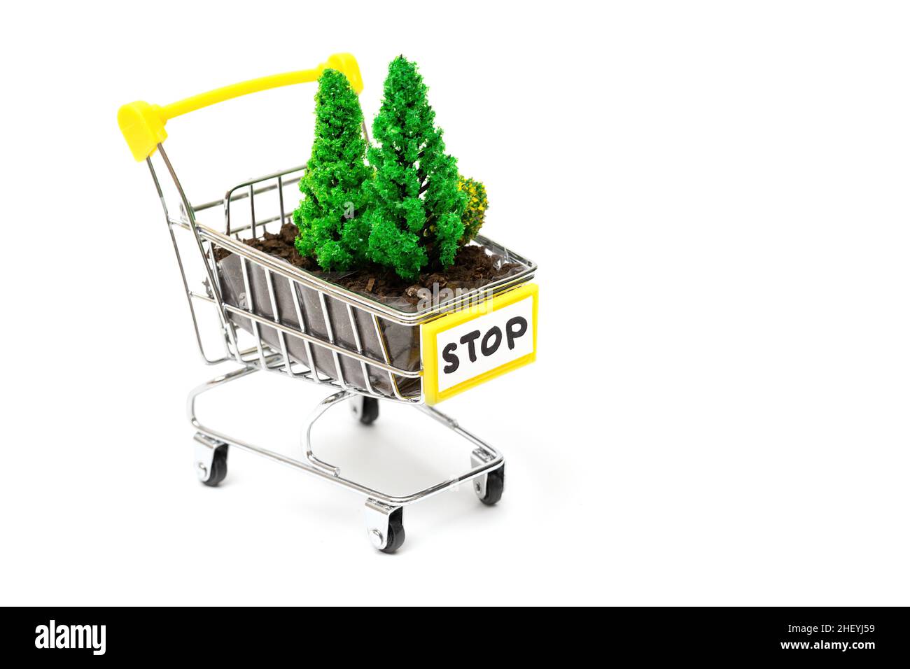 Soil and toy trees in a miniature shopping trolley with a stop sign isolated on white. Logging threat concept. Stock Photo