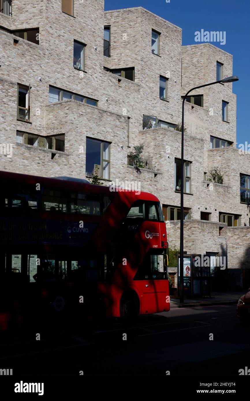 Routemaster bus going past new apartment block at 95 Peckham Road, Peckham, London, UK Stock Photo