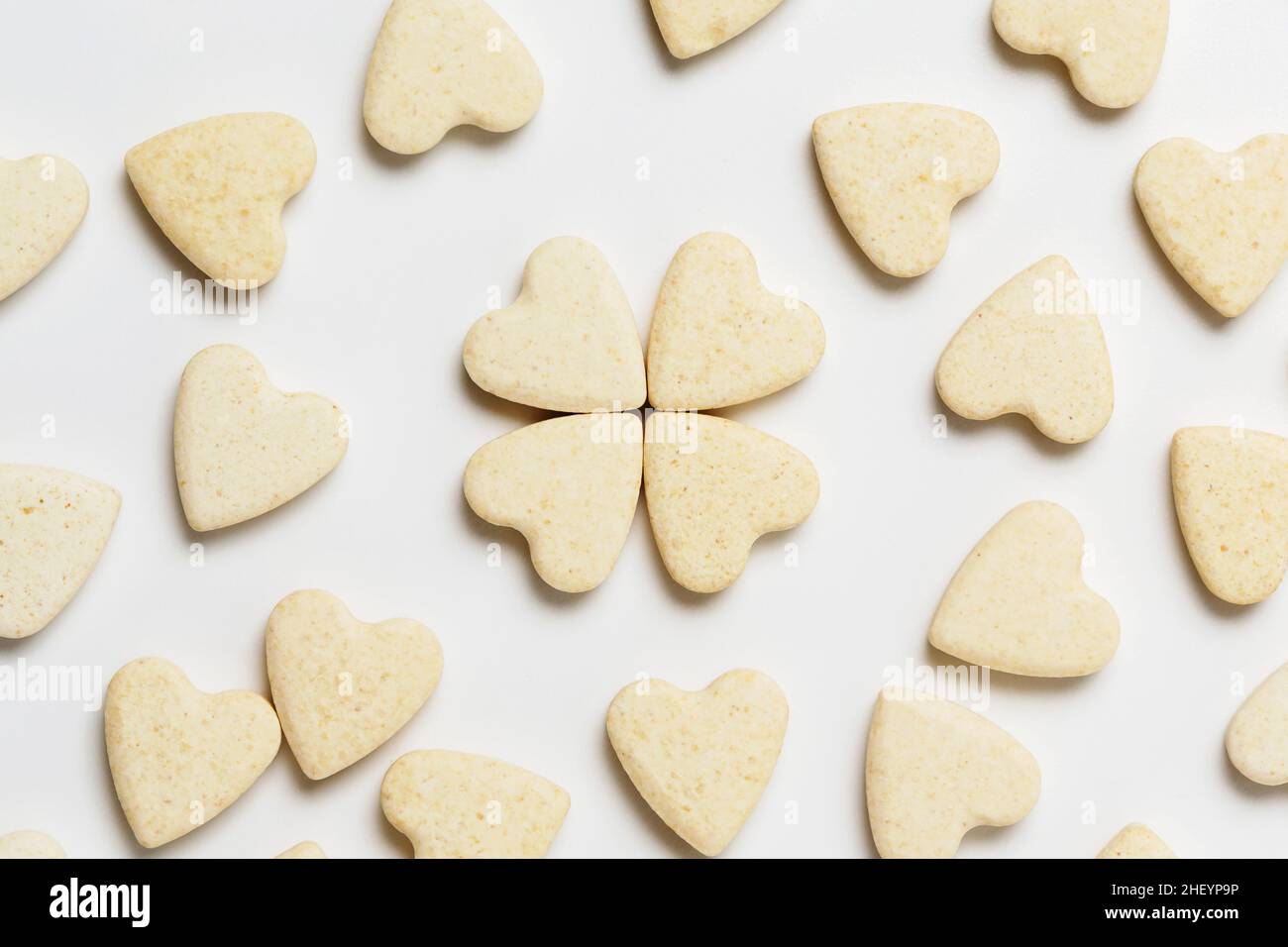 Saint Valentine day minimalistic greeting card, scattered heart-shaped sweet little cookies on white background, flat lay Stock Photo