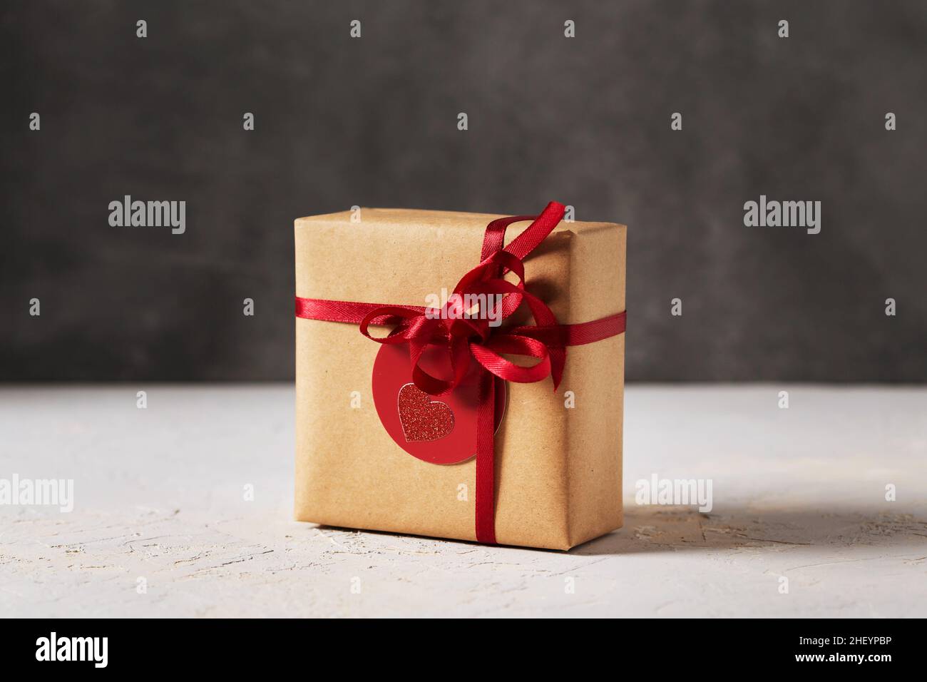 Valentines day present gift box wrapped in brown craft paper with red ribbon and red tag, side view Stock Photo
