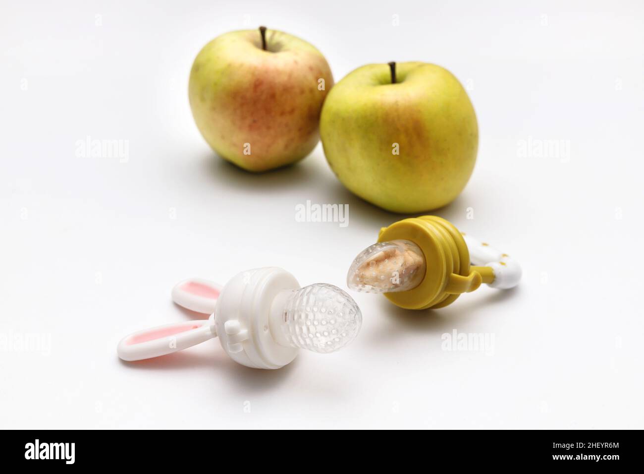 Nibbler with fresh apples on white table, closeup. Baby feeder. Stock Photo