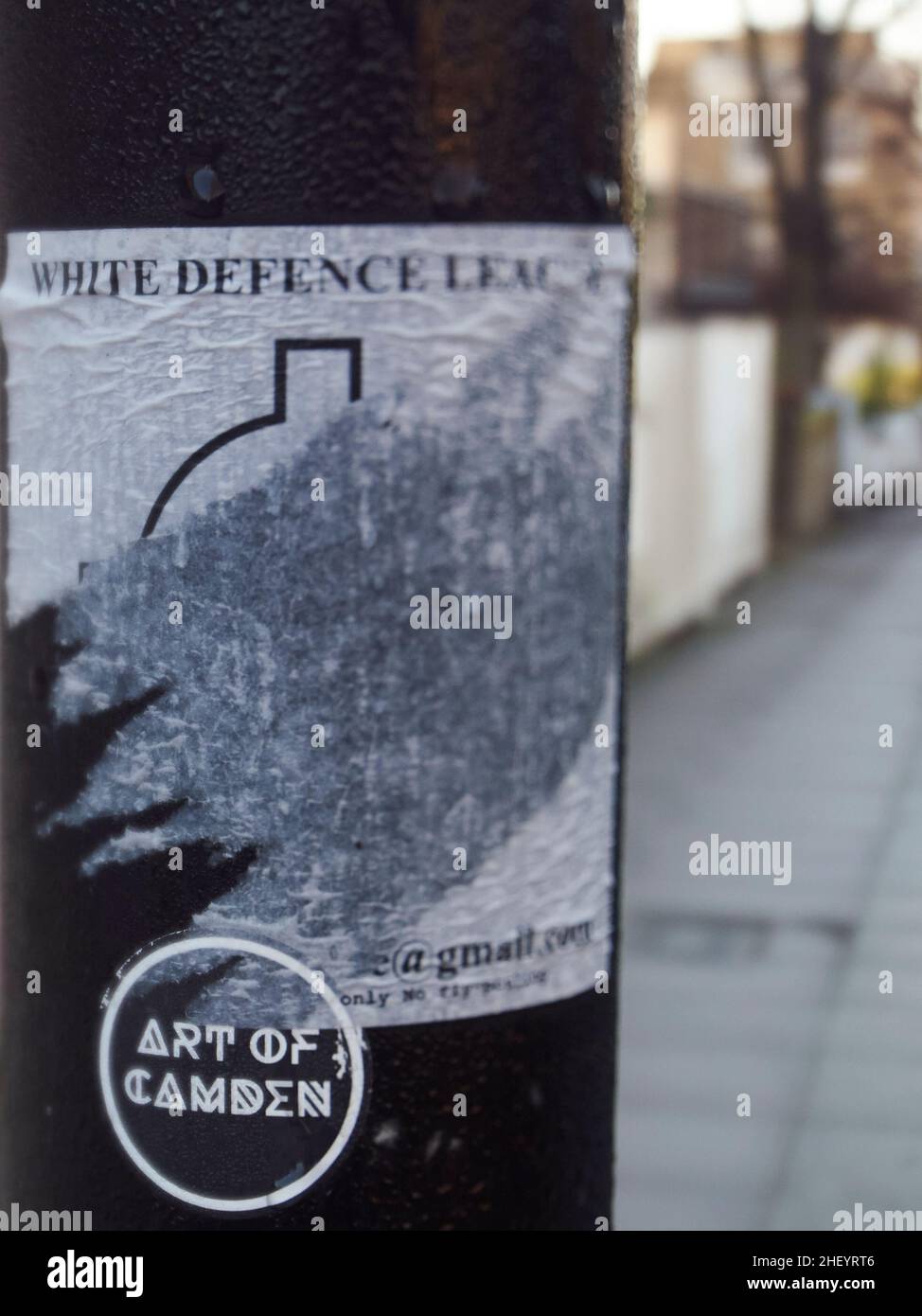Political debate by proxy on the streets of London, UK - a sticker supporting the far right White Defence League on a lamp post, torn and defaced. Stock Photo