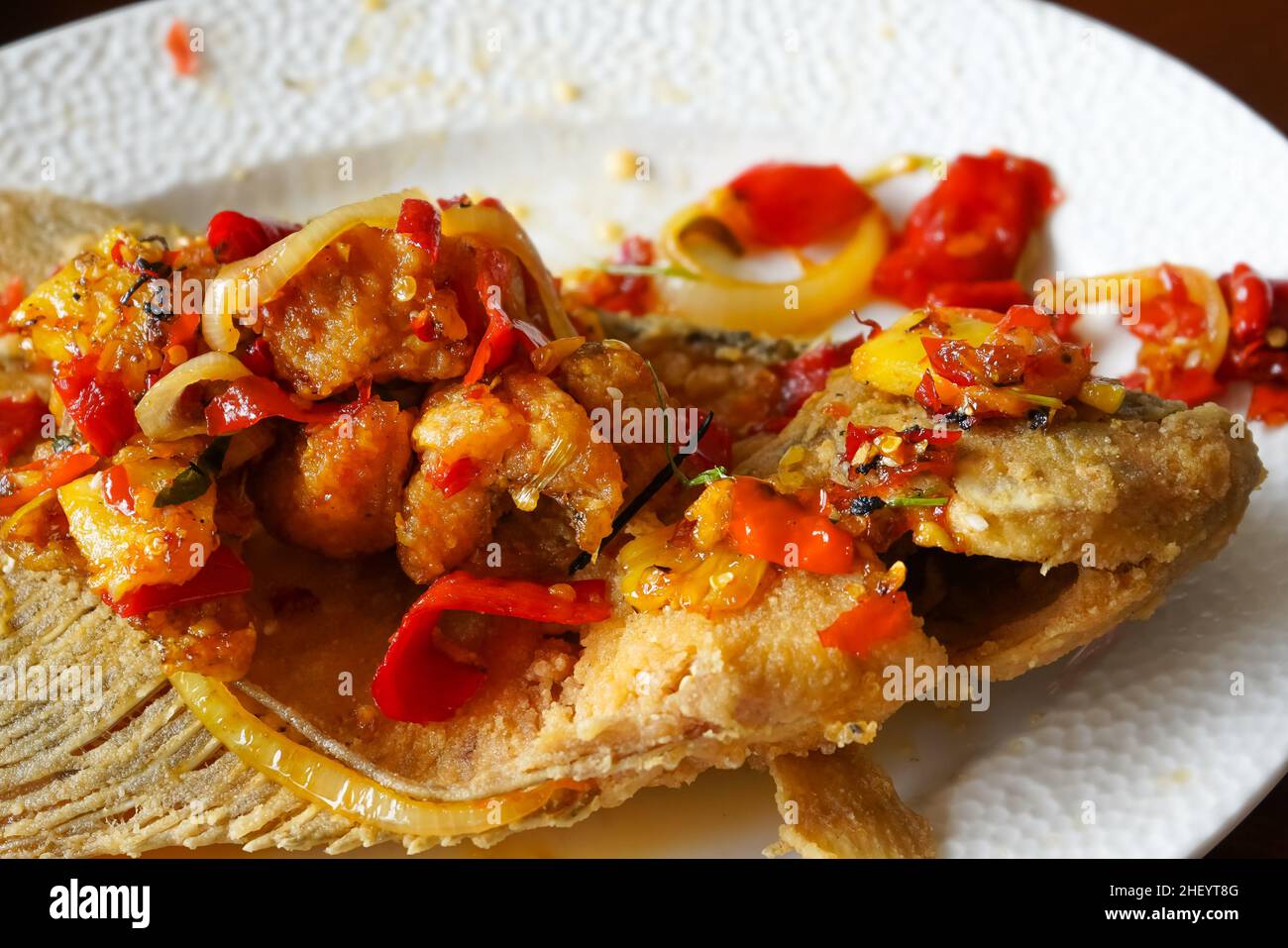 Spicy sweet and sour carp on a white plate which is one of the menu offerings from a seafood restaurant. Stock Photo