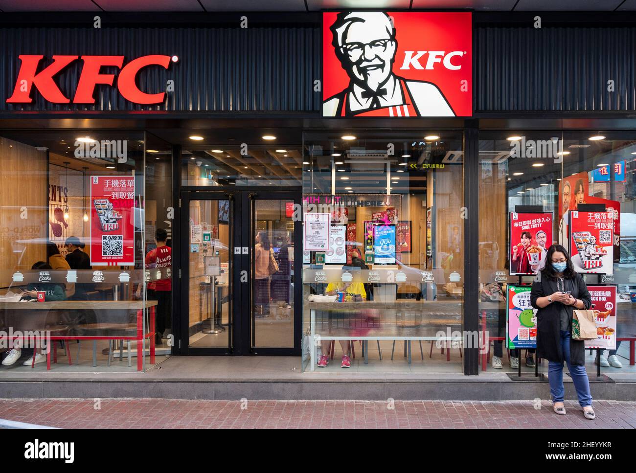 A pedestrian stands in front of the American fast food chicken