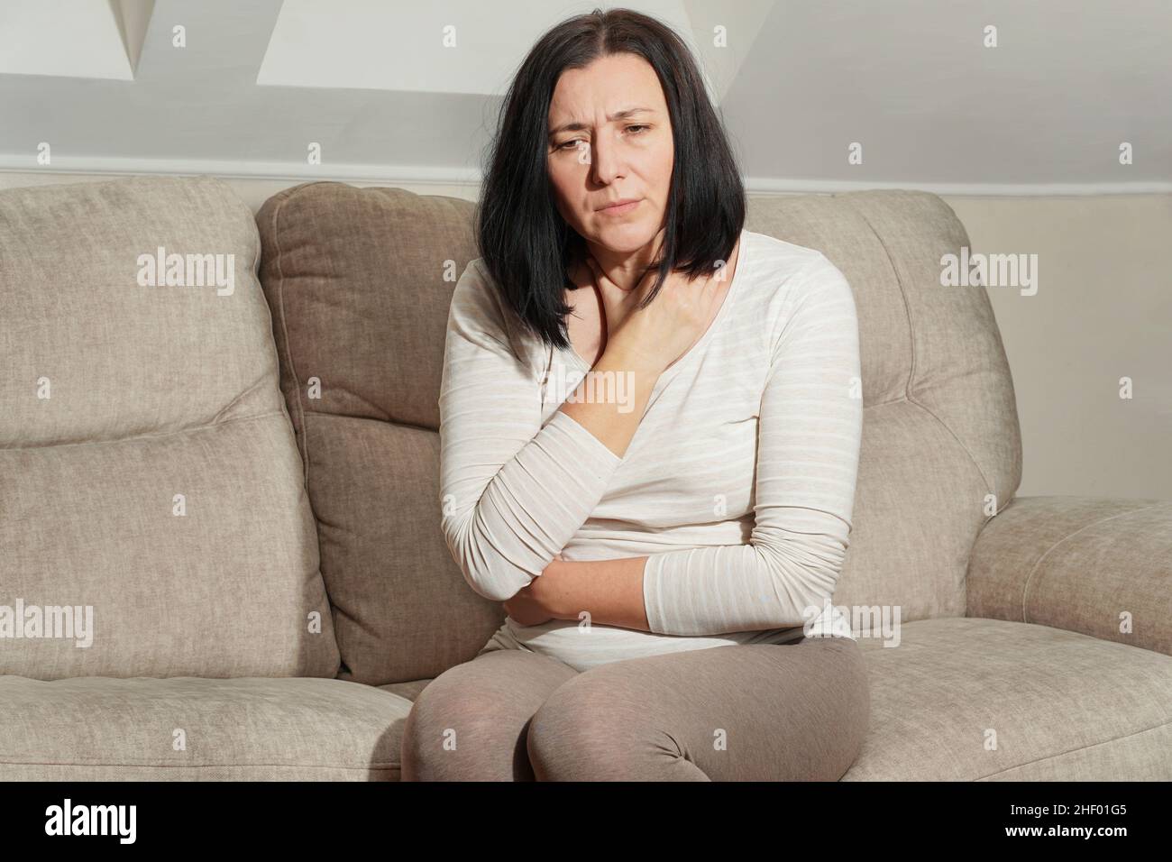 Middle aged mature pregnant woman suffering from headache and stomach ache, toxicosis at home. Abdominal pain, food poisoning, diarrhea, stomach ulcer Stock Photo