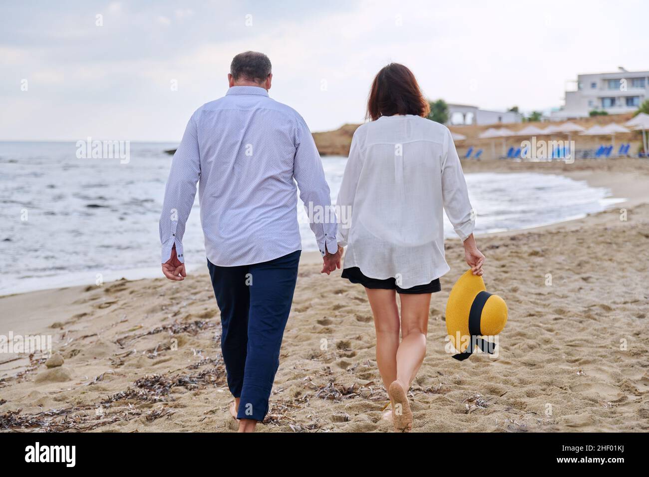 Happy middle aged couple walking together on the beach, back view Stock Photo