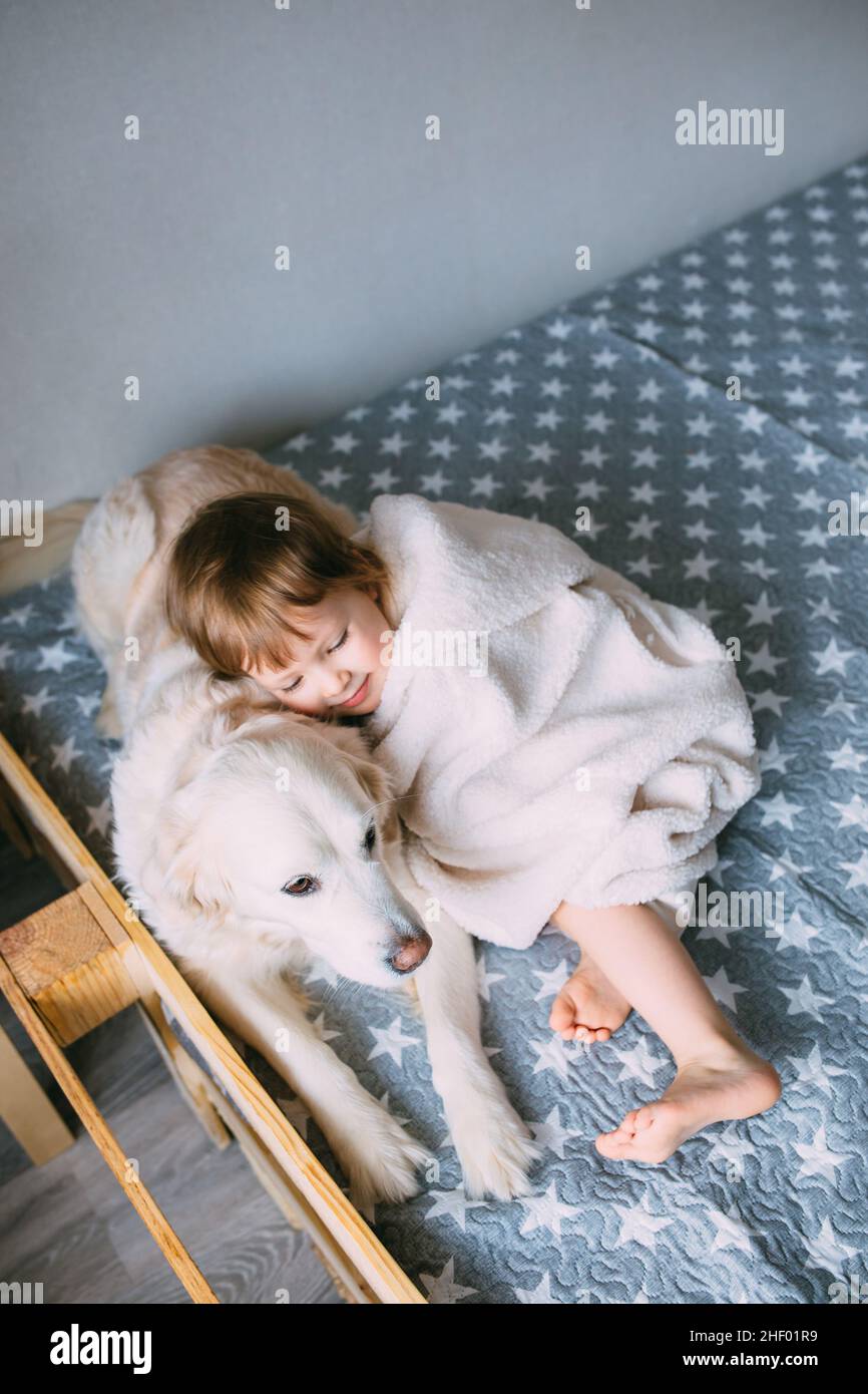 Cute baby and his labrador retriever at home on the bed. Stock Photo